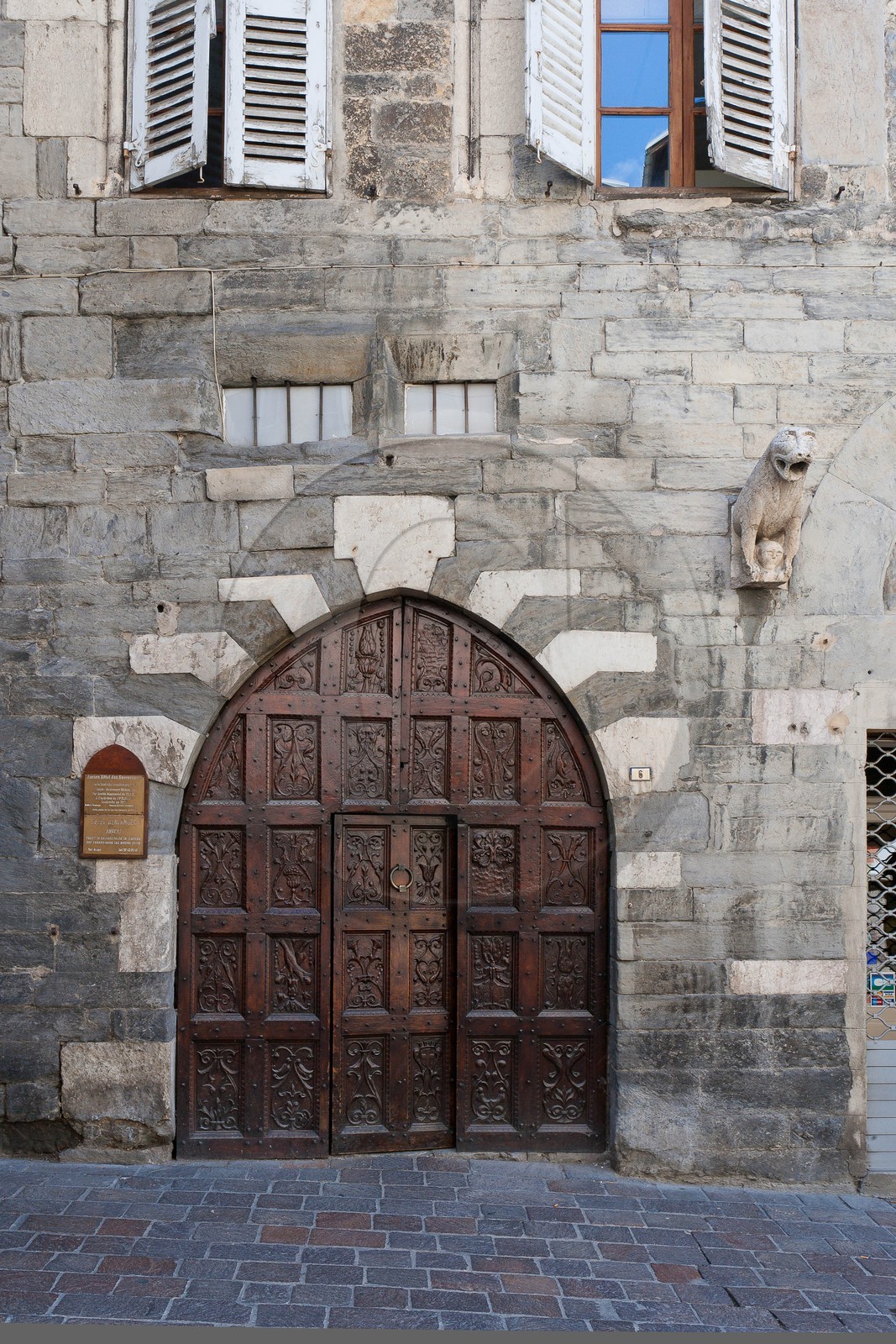 Embrun, Maison des Gouverneurs, Porte Renaissance accostée d'un lion à mi-corps tenant dans ses pattes une tête humaine Embrun, Maison des Gouverneurs, Porte Renaissance accostée d'un lion à mi-corps tenant dans ses pattes une tête humaine
